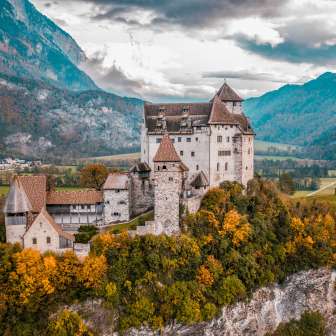 Panoramisch uitzicht op het middeleeuwse burcht Gutenburg in Liechtenstein met een kleurrijk herfstlandschap en alpine achtergrond