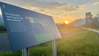 Informatiebord over het voedselveld van Vaduz met uitzicht op de Alpen bij zonsondergang - een leercentrum voor duurzame voeding in Liechtenstein.