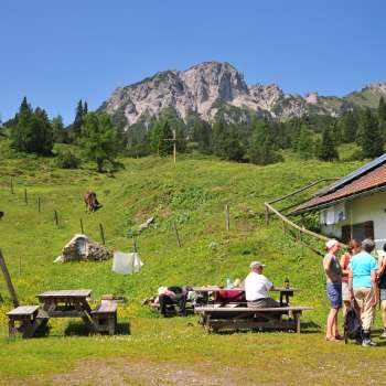 Uitzicht op de bergen vanaf Alpe Guschg, waar verschillende mensen even pauzeren en genieten van het uitzicht
