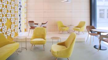 Modern café met stijlvolle gele fauteuils, minimalistische inrichting en lichte ramen