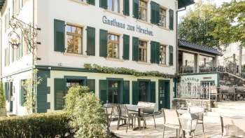 Uitnodigend terras met houten tafels en stoelen voor Gasthaus zum Hirschen