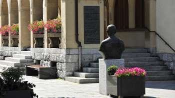 Zicht op de ingang van het stadhuis van Vaduz met bloemstukken, historische buste en brede stenen trappen - een cultureel herkenningspunt in het centrum van Vaduz.