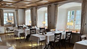 Lichte, klassieke eetkamer met witte tafelkleden en houten vloer.