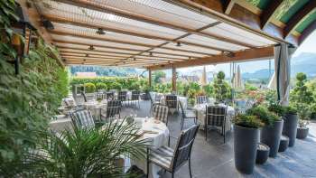 Elegant restaurantterras met overdekte tafels en panoramisch uitzicht op de Liechtensteinse Alpen.