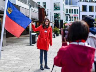 Stadsgids toont de Liechtensteinse vlag tijdens een rondleiding door het centrum van Vaduz