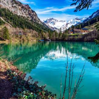 Kristalhelder bergmeer Gänglemeer in Steg, Liechtenstein - omringd door bossen, bergen en fris lentegroen