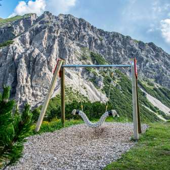 Hangschommel op het Schommelpad Malbun met uitzicht op steile rotswanden en alpenlandschap in Liechtenstein