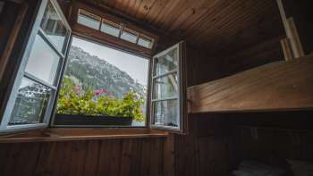 Raamuitzicht vanuit de slaapkamer: Uitzicht op het berglandschap vanuit een eenvoudige slaapkamer met stapelbed in de Gafadurahütte