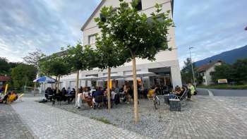 Levendig terras van St. Martins Pub am Platz met schaduwrijke bomen en gasten aan tafels