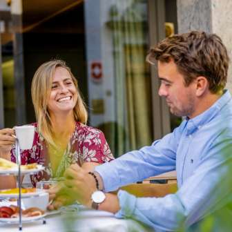 Een stel geniet van een al fresco ontbijt op een terras in Vaduz, omgeven door een ontspannen sfeer