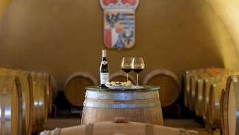 Sfeervolle wijnproeverij in de wijnkelder van de Princely Winery met twee glazen en een fles rode wijn op een houten vat.