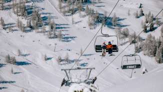 Twee skiërs zitten in de stoeltjeslift boven het besneeuwde skigebied Malbun in Liechtenstein