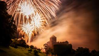 Kasteel van Vaduz in Liechtenstein bij nacht met groot vuurwerk in de lucht - sfeervolle opname met licht en mist