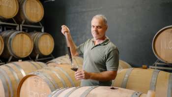Harry Zech haalt wijn uit het barriquevat om te proeven met een pipet - traditioneel wijnmaken in Schaan.