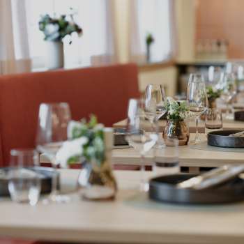 Close-up van stijlvol gedekte tafels in het RUUF-restaurant met donker servies en bloemenvazen