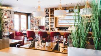 Het interieur van PUR Restaurant & Bar wordt gekenmerkt door elegante rood gestoffeerde stoelen en stijlvol gedekte tafels.