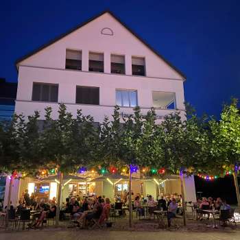 Sfeervolle avondopname van de St. Martins Pub met verlicht terras en kleurrijke sprookjesverlichting.
