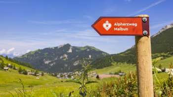 Wegwijzer pad van het Alpijns hart met het bergdorp Malbun op de achtergrond