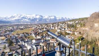 Telescoop op het uitzichtpunt Schlossweg Känzile met uitzicht op Vaduz en het besneeuwde Alpenpanorama op de achtergrond.