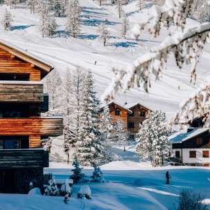Gezellige chalets in het wintersportoord Malbun omringd door besneeuwde bomen en skipistes op de achtergrond