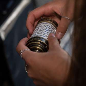 Close-up van handen met een mysterieus combinatieslot in de Malbun Escape Room