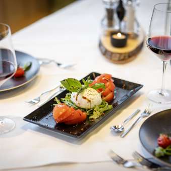 Verse tomaat en mozzarella salade met rode wijn op een gedekte tafel in het JUFA Hotel Malbun