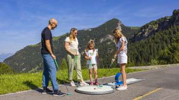  Gezin speelt samen minigolf in de bergen van Malbun in de stralende zon