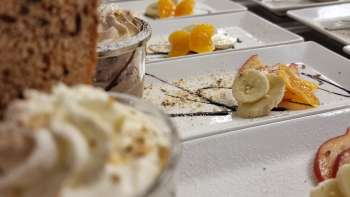 Rijk gedekte tafel met kleine dessertglaasjes, fruit en garnering voor een zoet buffet