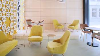 Modern café met stijlvolle gele fauteuils, minimalistische inrichting en lichte ramen