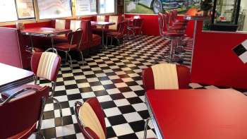Het interieur van de 1950 American Diner rode tafels en een zwart-witte vloer