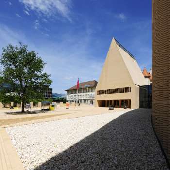 Zicht op het helder geplaveide Peter-Kaiser-Platz voor het parlementsgebouw in Vaduz met zijn moderne architecturale ensemble.