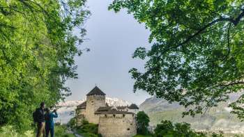 Twee mensen genieten vanaf het wandelpad van het uitzicht op kasteel Vaduz