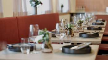 Close-up van stijlvol gedekte tafels in het RUUF-restaurant met donker servies en bloemenvazen