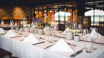 Uitnodigende brouwerijzaal met lange houten tafels, fustdecoraties en stijlvolle verlichting