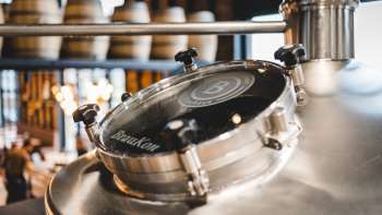 Close-up van een glimmende brouwketel met kijkvenster en brouwerijlogo in de Liechtensteinse brouwerij