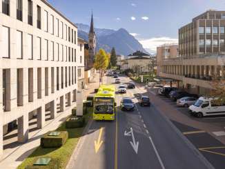 Een LIEmobil-bus rijdt door Vaduz tegen de achtergrond van de Alpen en moderne architectuur