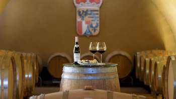 Sfeervolle wijnproeverij in de wijnkelder van de Princely Winery met twee glazen en een fles rode wijn op een houten vat.