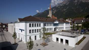 Het Domusgebouw in Schaan met zijn witte gevel en uitzicht op de parochiekerk - een cultureel centrum en ontmoetingsplaats in het hart van Liechtenstein