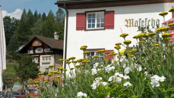 Traditionele bergherberg met rode luiken en bloeiende bloemen op de voorgrond