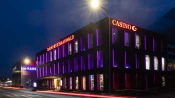Het Casino Schaanwald in het donker, indrukwekkend verlicht met paarse lichtaccenten - een populaire bestemming voor nachtbrakers in Liechtenstein.