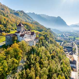 Uitzicht op Kasteel Vaduz in Liechtenstein met herfstkleuren, bergen en het Rijndal op de achtergrond