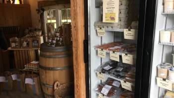Streekassortiment in de boerderijwinkel van Hedihof - koelkast met verpakte vleeswaren en rustieke verkoopruimte.