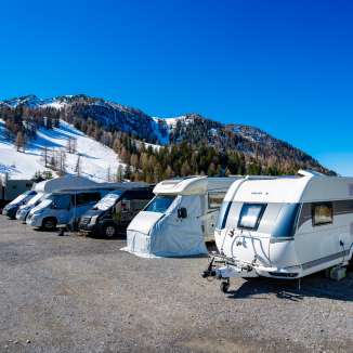 Campers en caravans staan geparkeerd op een besneeuwde kampeerplaats in Malbun met uitzicht op de Alpen