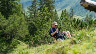 Rolstoelgebruiker geniet van het alpenlandschap in Malbun - barrièrevrije toegang tot de natuur in Liechtenstein
