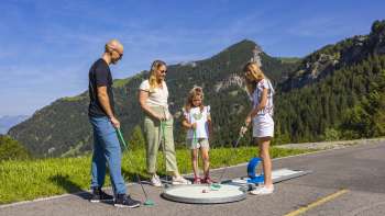  Gezin speelt samen minigolf in de bergen van Malbun in de stralende zon