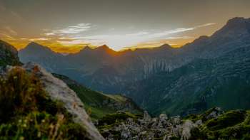 Zonsondergang op de bergkam - De zon zakt achter de bergtoppen en baadt het alpenpanorama in warme avondkleuren
