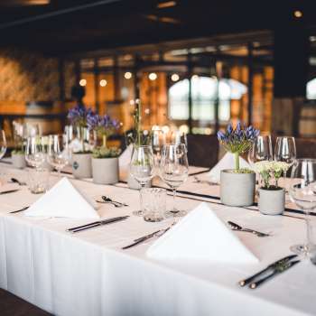 Uitnodigende brouwerijzaal met lange houten tafels, fustdecoraties en stijlvolle verlichting