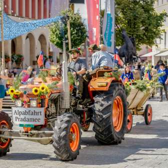 Feestelijk versierde tractor met aanhanger bij de Pradamee 2020 Alpine afdaling in Liechtenstein, omringd door toeschouwers