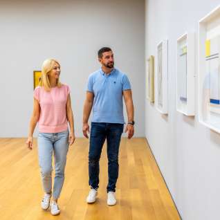 Een stel wandelt door het Kunstmuseum Liechtenstein in Vaduz en bekijkt hedendaagse kunstwerken aan de muur.