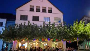 Sfeervolle avondopname van de St. Martins Pub met verlicht terras en kleurrijke sprookjesverlichting
